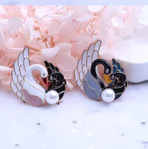 Detalle de broches de cisne con acabado de esmalte, cristales y perlas blancas finas