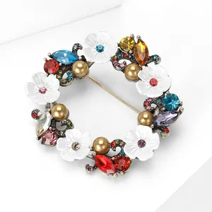 Vue macro d'une broche couronne florale vintage avec strass colorés et perles