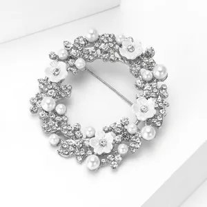 Makroaufnahme einer silbernen Kranz-Brosche mit Perlen, Strass und weißen Blumen-Details