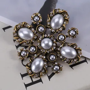 Vintage gold cross brooch with pearls and rhinestones on a magazine background