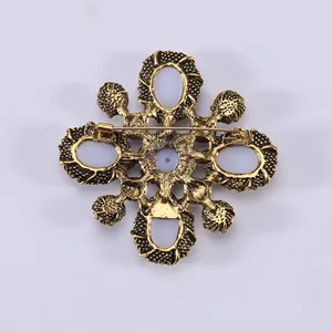 Vintage gold cross brooch with white stone inlay and detailed relief on the back