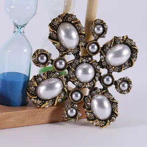 Vintage antique style gold flower brooch with white faux pearls and crystals on white background