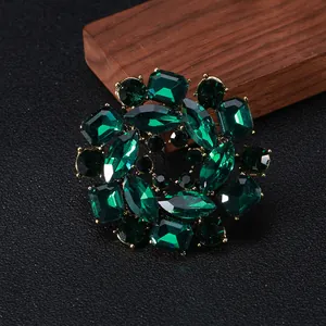 Macro shot of circular vintage brooch featuring emerald green crystals and gold finish
