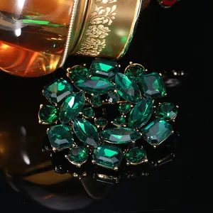 Detail of vintage flower brooch featuring emerald green crystals and gold setting