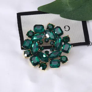 Elegant emerald green crystal flower brooch pin with vintage gold-tone petal setting