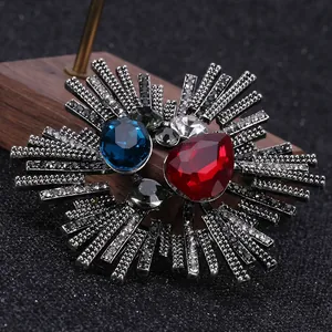 Macro detail of retro starburst brooch with red pear-cut gems and gun black metal finish