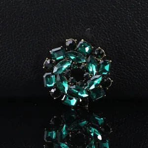 Detail of dark green crystal flower brooch with gold plating on black textured background