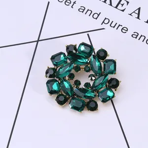 Macro view of vintage gold flower brooch featuring deep green mixed-cut crystal gemstones