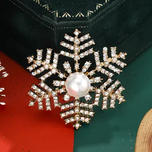 Macro detail of snowflake brooch with gold metal finish, white pearl and sparkling crystals