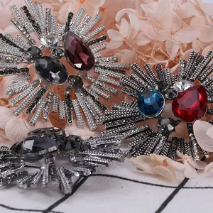 Vintage sunburst brooch pins with colorful teardrop gemstones on plaid background