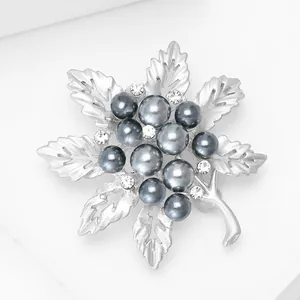 Détail macro d'une broche feuille argent mat avec perles grises et cristaux étincelants