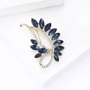 Close-up of vintage gold alloy brooch with dark blue marquise crystals and pavé diamonds