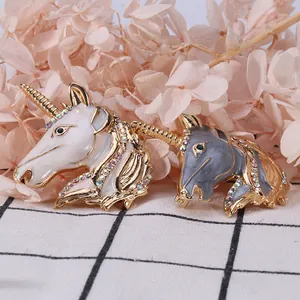 Detail of white and grey enamel unicorn brooches with colorful rhinestones and gold plating