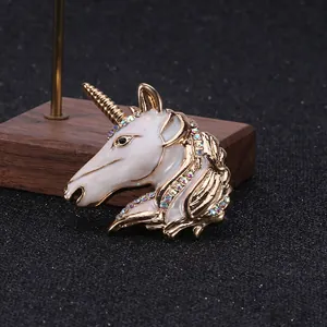 Detailed close-up of a golden unicorn brooch with white enamel and colorful rhinestones