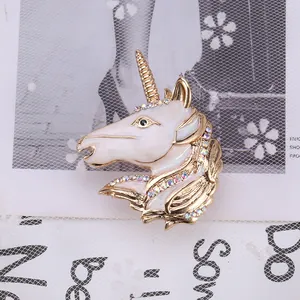 Detailed macro of golden unicorn brooch with white enamel and sparkling colored rhinestones