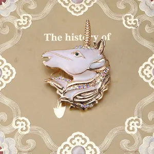 Close-up of golden unicorn brooch with white enamel, colorful rhinestones and crystal eye