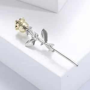 Elegant rose brooch in gold and silver metal finish on a minimalist display