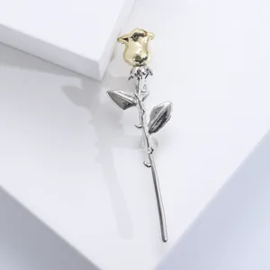 Elegant rose brooch in gold and silver finish on minimalist white background
