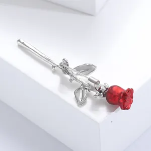 Detail of red rose brooch with silver textured leaves and stem on white pedestal