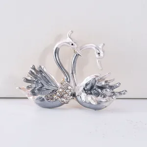 Élégante broche double cygne en émail blanc et strass scintillants finition argentée