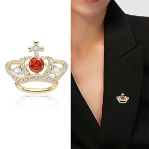 Luxurious gold crown brooch with red zircon and cross details on black suit jacket