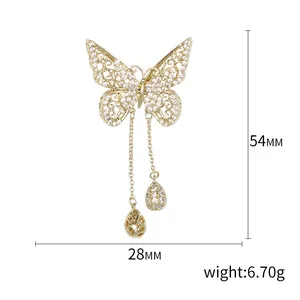 Broche papillon dorée avec zircons étincelants, ailes ajourées et pampilles de chaîne