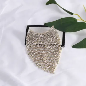 Détail de la broche pampille en cristal avec strass sur tissu blanc élégant