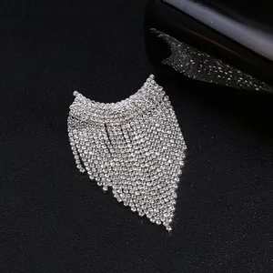 Gros plan d'une broche à franges argentée avec cristaux brillants sur fond noir