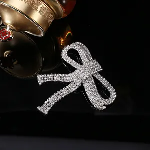 Elegant silver bow brooch with tassels and sparkling rhinestones on dark background