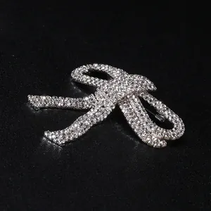Detailed close-up of a bow-knot brooch with silver-finish and sparkling rhinestones
