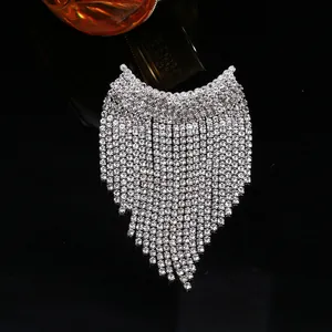 Gros plan d'une broche à pompons en strass argentés avec de longues franges sur fond noir