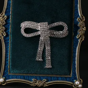 Close-up of sparkling rhinestone bow brooch with tassels on a luxury velvet display