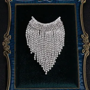 Détail d'une broche à pompon en strass argentés sur un plateau en velours vert