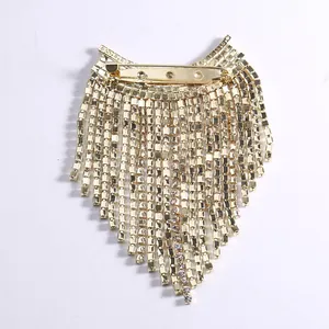Broche élégante à pompons dorés avec strass étincelants et chaînes en cascade sur fond blanc