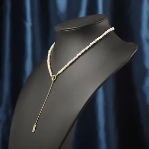 Dettaglio di elegante collana di perle con chiusura a ginocchiera dorata e pendente a catena