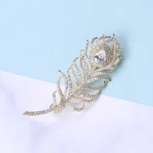 Détail de l'élégante broche plume dorée avec zircons scintillants et cristal en goutte
