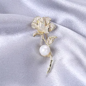 Dettaglio macro dell'elegante spilla a rosa dorata con zirconi e una perla bianca