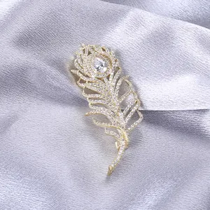 Vue détaillée d'une broche plume dorée sertie de zircons blancs et d'une pierre en forme de goutte