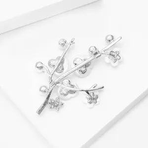 Close-up of silver plum blossom brooch with white resin petals and zircon accents