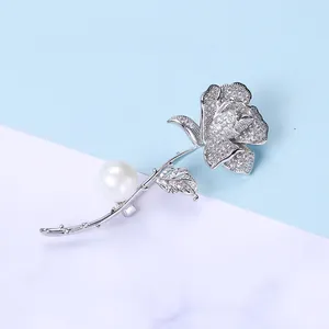 Dettaglio della spilla a rosa con pavé di zirconi ed elegante accento di perla bianca