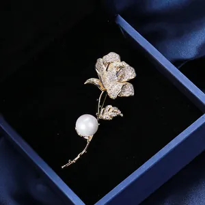 Dettaglio macro di una spilla a rosa con zirconi scintillanti e perla bianca su velluto