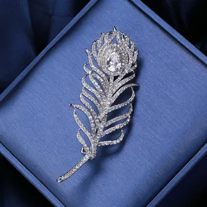 Gros plan sur broche plume argentée avec oxydes de zirconium dans un coffret bleu