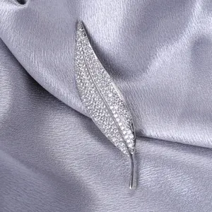Macro view of micro-pasted zircon leaf brooch in silver finish on silk fabric