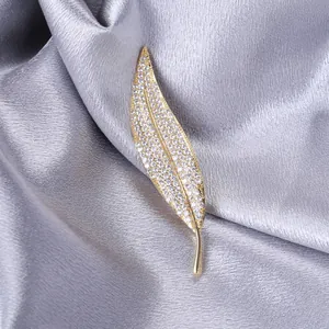 Macro detail of leaf-shaped brooch with inlaid cubic zirconia on grey silk fabric