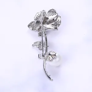 Dettaglio di spilla a rosa argentata con petali in zircone e perla bianca lucente