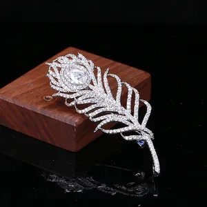 Broche élégante en forme de plume argentée avec zircons sur fond miroir noir