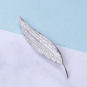 Macro shot of silver leaf brooch featuring micro-pave cubic zirconia on marble background