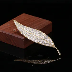 Elegant gold leaf brooch with white zircon pavé setting shown on a premium dark background