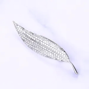 Detailed close-up of leaf brooch with micro-pave zircons on marble background