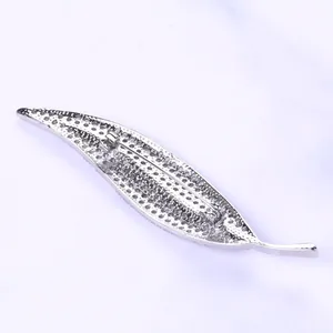 Macro shot of silver leaf-shaped brooch with micro-paved white zircons and metal clasp
